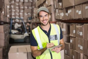31351510 - warehouse worker smiling at camera with clipboard in a large warehouse