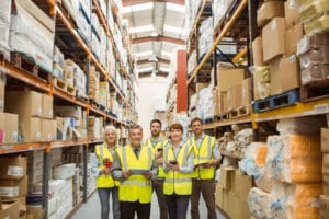 36345279 - smiling warehouse team looking at camera in a large warehouse