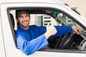 36390326 - delivery driver smiling at camera in his van outside the warehouse