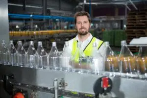 young-male-worker-standing-by-production-line-juice-factory_107420-96037