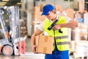 21401636 - warehouseman with protective vest and scanner, scans bar-code of package, he standing at warehouse of freight forwarding company