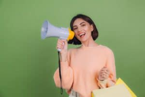 young-woman-casual-peach-sweater-isolated-green-olive-color-wall-shout-megaphone-holding-shopping-bags-announces-discounts-sale-promotion_343596-5130
